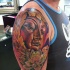 Tatuaje en el brazo, buda entre hojas y un loto