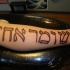 Tatuaje de escrito hebreo grande en la pierna