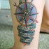 Tatuaje en la pierna, compás náutico multicolor y escrito en inglés