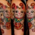 Beautiful looking colored shoulder tattoo of maneki neko japanese lucky cat statuette and red flowers