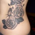 Großes Tattoo mit schwarzen und grauen Rosen an der Seite
