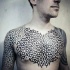 Tatuaje en el pecho y hombros, ornamento geométrico de tinta negra