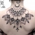 Big black ink upper back tattoo of flower shaped ornaments