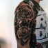 Tatuaje en el brazo, micrófono retro entre flores rosas, dibujo negro blanco