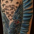 Tatuaje en el antebrazo, cuervo amenazante con alas desplegadas
