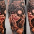 Biomechanical style colored leg tattoo of woman face with strange camera
