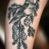 Tatuaje en el brazo, pájaro en la rama de abeto