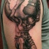 Black and gray style colored shoulder tattoo of man holding planet