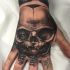 Black and gray style detailed hand tattoo of monster skull with eye