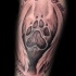 Black and gray style detailed tattoo of animal paw print with wings and lettering