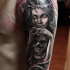 Black and gray style shoulder tattoo of demonic woman with human skull