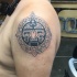 Black and white circle shaped shoulder tattoo of ancient stone tablet