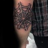 Black and white spiderweb tattoo on elbow with dark shadow