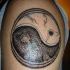 Tatuaggio sul deltoide il disegno in stile Yin-Yang