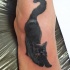 Tatuaje de gato negro, que se estira, en el pie