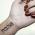 Tatuaje en la muñeca,
 inscripción hebrea,  letras gruesas negras