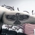 Black ink biceps tattoo of ancient bird stylized with tribal ornaments