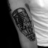 Black ink engraving style biceps tattoo of skeleton hand with vintage microphone