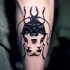 Tatuaje en el antebrazo,
escarabajo negro surrealista con dos caras de chicas