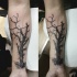 Black ink forearm tattoo of dark tree