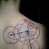 Black ink geometrical style scapular tattoo of various circles