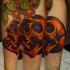 Black ink leg tattoo of human skull with cute flowers