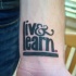 Tatuaje en la muñeca, frase vive y aprende, letra gruesa