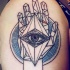 Black ink shoulder tattoo of human hand with eye tattoo in geometrical style