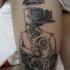 Black ink thigh tattoo of human body with old camera and hat