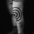 Black ink watercolor style hypnotic symbol tattoo on knee