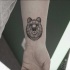 Black ink wrist tattoo of cartoon bear head
