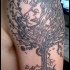 Tatuaje de un árbol negro en mitad de la manga para hombre.