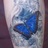 Tatuaggio colorato sulla gamba la farfalla blu tra i fiori