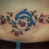 Tatuaje en la espalda baja, 
delfín y tallo con flores