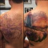 Breathtaking natural looking old lighthouse tattoo on back with flowers and lettering