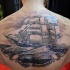 Breathtaking very detailed upper back tattoo of big sailing ship with waves