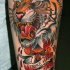 Tatuaje en el antebrazo, tigre furioso perforado por espada y inscripción