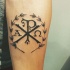 Tatuaje en el antebrazo,
cristograma  Chi Rho  con corona de laurel