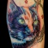 Tatuaggio realistico la testa del gatto colorata con il ramo fiorito