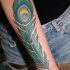 Tatuaggio colorato sul braccio la piuma del pavone