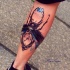 Cool looking colored leg tattoo of big clock made from big bug