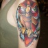 Cool looking colored shoulder tattoo of funny owl with tree branch