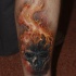 cranio nero brucia in fuoco tatuaggio sulla gamba