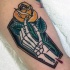 Tatuaje en el brazo, ataúd con mano esquelético y rosa amarilla