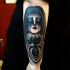 Dark black and white arm tattoo of woman with hood and burning heat stylized with skull