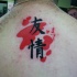 Dark black Asian hieroglyphs with red ink elements tattoo on man's upper back