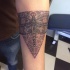 Designed dragonfly on triangle detailed dark colored tattoo on forearm in dotted work