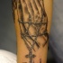 Muy detallado tatuaje en tina oscura las manos rezando con un rosario
