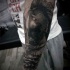 Dramatic black ink Spartan warrior tattoo on forearm combined with skulls