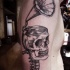 Engraving style black ink shoulder tattoo of large human skull combined with gramophone